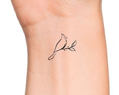 a small bird tattoo on the wrist is shown in black ink, and it has a branch