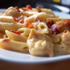 a white plate topped with pasta covered in sauce and meats on top of it