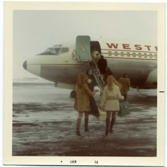 two women are boarding an airplane on the tarmac with another woman standing next to it