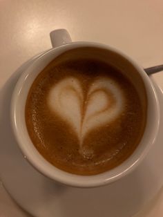 a cup of coffee with a heart drawn in the foam on it's side