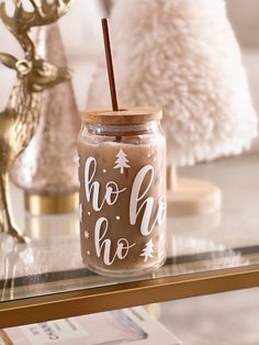 a glass jar with a straw in it sitting on a table next to two deer figurines