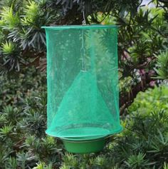 a green bird feeder hanging from a tree