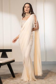 Ivory pre-draped saree with embellished border using crystal, sequins and mirror work. Paired with a blouse with all over crystal, mirror embellishments.
Components: 2
Pattern: Embellished
Type Of Work: Crystals, Mirror, Sequins
Neckline: V Neck
Sleeve Type: Sleeveless
Fabric: Blouse: Net, Saree: Georgette
Color: Ivory
Other Details: 
Length:
Blouse: 14 inches
Saree: 42 inches
Occasion: Sangeet - Aza Fashions Festive Embellished Pre-draped Saree For Reception, Glamorous Georgette Choli With Pearl Embroidery, Designer Pre-draped Off White Saree With Sheer Dupatta, Off White Pre-draped Saree With Dupatta For Reception, Traditional Pre-draped Saree With Pearl Embroidery For Evening, Off White Designer Pre-draped Saree For Festive Occasions, Glamorous Pre-draped Saree With Mirror Work For Reception, Wedding Pre-draped Saree With Mirror Work, Elegant Draped Sharara With Mirror Work