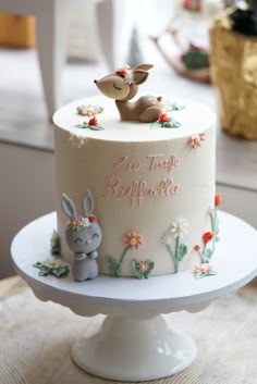 a white cake decorated with flowers and rabbits