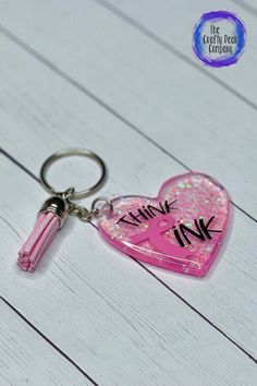 a pink heart shaped keychain with the words think ink on it and a pen sticking out of it