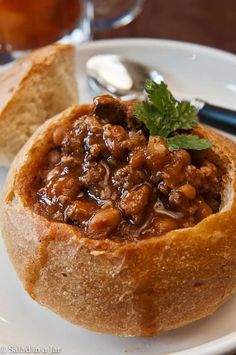 a white plate topped with a bowl of chili and bread