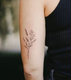 a woman's arm with a small flower tattoo on the left side of her arm