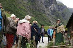 a group of people standing around each other in front of a mountain side area with mountains behind them