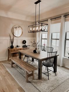 a dining room table and bench in front of large windows