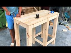 a man standing next to a table made out of wooden planks with tools on it