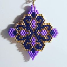 a beaded ornament is hanging on a white surface with a gold chain