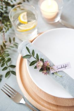 a place setting with napkins, flowers and candles