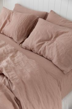 an unmade bed with pink sheets and pillows