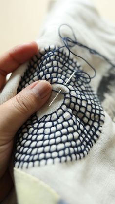 a person is stitching something on a piece of cloth