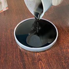 a person pouring water into a bowl on top of a wooden table