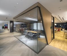 an empty conference room with glass walls and wooden flooring is seen in this image