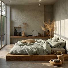 a large bed sitting in the middle of a room next to a wall with lots of windows