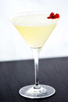 a white cocktail with a red flower on the rim