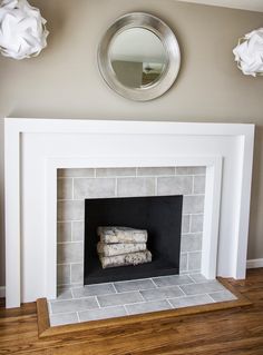 a white fireplace with some towels stacked on it's mantle next to a mirror