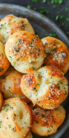 a plate filled with mini pizzas covered in cheese and herbs