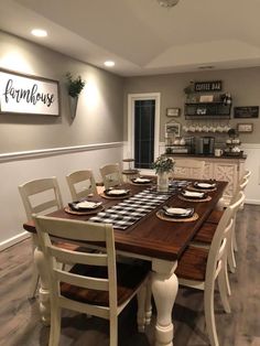 the dining room table is set with place settings for eight people, and there is a sign on the wall above it