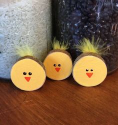 three little yellow chicks sitting on top of a wooden table next to a jar filled with rice