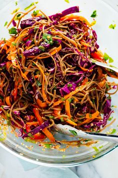 a glass bowl filled with noodles and vegetables