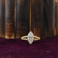 a diamond ring sitting on top of a purple velvet covered table next to stacks of books