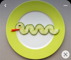 a plate with cucumber slices cut in the shape of letters on it and an orange toothpick sticking out of the middle