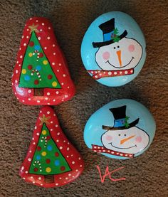 three painted rocks with christmas trees and snowmen on them, sitting on the floor