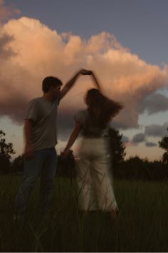 two people standing in the grass with their arms around each other as they hold hands