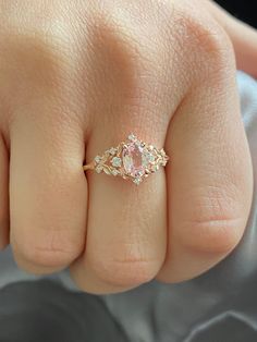 a woman's hand with a pink diamond ring on top of her finger,