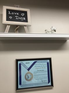 an award plaque is hanging on the wall next to a framed certificate that reads i love dogs