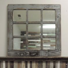 a mirror that is on top of a wooden shelf in front of a striped wall