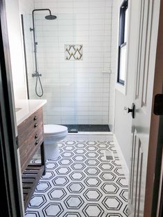 a white bathroom with black and white floor tiles