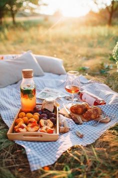 a picnic blanket with food and wine on it in the middle of an open field