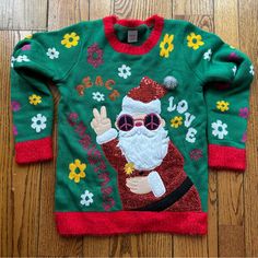 a green christmas sweater with a santa clause on the front and peace sign on the back