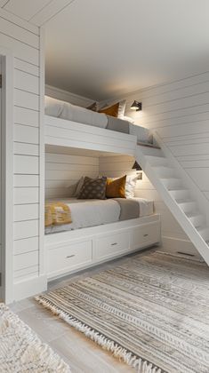 a white bunk bed sitting under a set of stairs next to a stair case in a bedroom