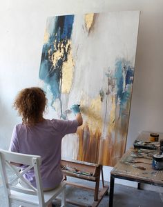 a woman is painting on an easel in her studio