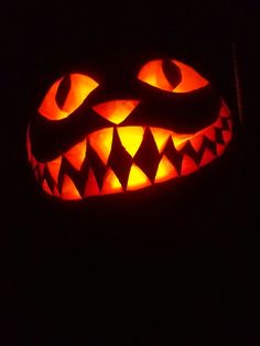 a carved pumpkin with glowing eyes in the dark