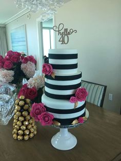 a black and white striped cake with pink flowers on the table in front of it