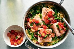 a pan filled with meat and vegetables next to a bowl of tomatoes, green beans and cherry tomatoes