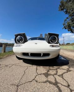 the front end of a white sports car with speakers on it's headlamps