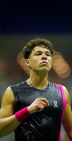 a male tennis player in a black shirt and pink armbands is looking up at the sky