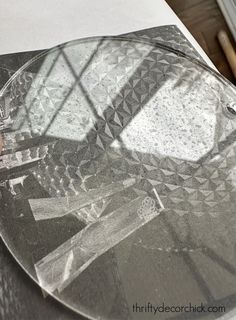 a glass plate sitting on top of a table next to a wooden chair and window