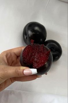 a hand holding a small bowl filled with cherries on top of a white table