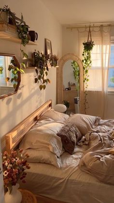 an unmade bed in a bedroom with plants on the windowsill and potted plants