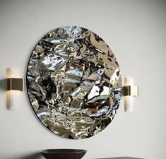 a round mirror hanging on the wall above a table with a bowl in front of it