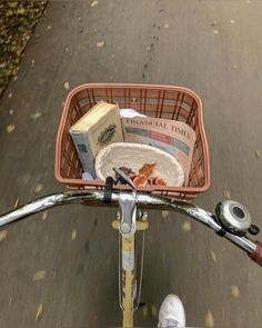 a basket on the back of a bicycle with books in it and someone's feet