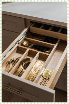 an open drawer with utensils and spoons in it on top of a table